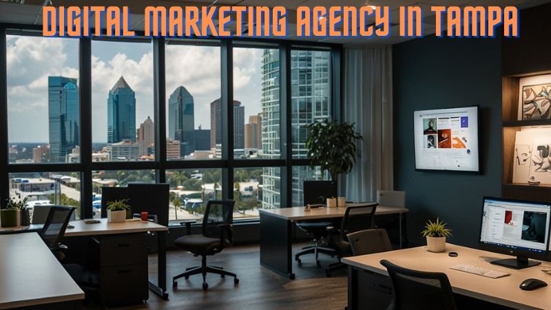 A modern digital marketing agency office in Tampa with a city skyline view, featuring workstations, computers displaying marketing content, and a professional workspace.